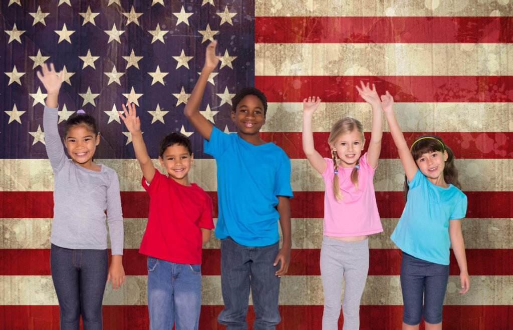 Children & Family en Estados Unidos-alumnos de primaria sonriendo detrás de bandera de Estados Unidos